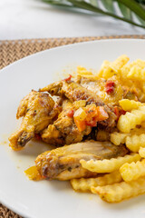 Cooked chicken wings and french fries on white plate