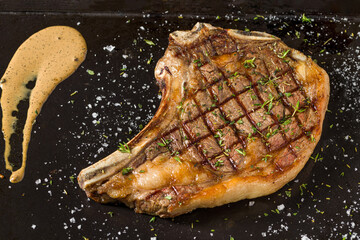 Juicy grilled Dallas steak with sauce on wooden serving board