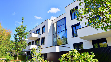 Modern apartment building with balconies and greenery. The structure features a glass wall and lush...