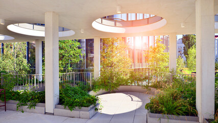 Modern luxury office building.The structure features a glass and concrete walls, showcasing contemporary architecture. The green surroundings of office buildings. Trees and shrubs in the city.