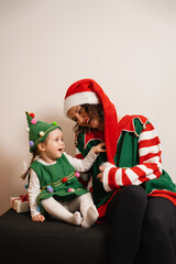 Happy mom in Santa hat with child dressed as Christmas tree celebrating holiday season