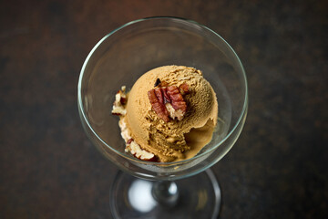 caramel ice cream scoop with nut  in glass bowl