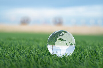 Transparent glass globe on green grass symbolizes environmental sustainability, global awareness, and ecological responsibility in protecting our planet for a greener future.