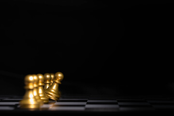 Golden pawns on a chessboard with one piece leaning forward, symbolizing individuality, courage, leadership potential, breaking the norm, thinking differently, and standing out in a team.