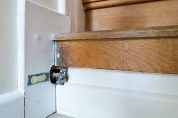 Focus on a water shutoff tap seen at the base of a wooden staircase in an old English cottage. The...