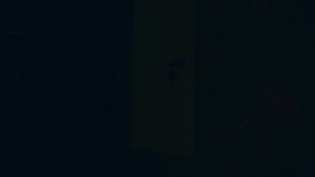 Blackout, No electricity. A man with a candle in the dark checks the electrical panel in the room during a power outage.