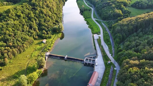 The Kupa river with a hydroelectric power plant near the road in a dense green forest