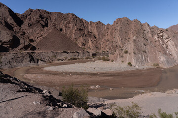 Pyramid-shaped hill in rocky desert valley with winding river