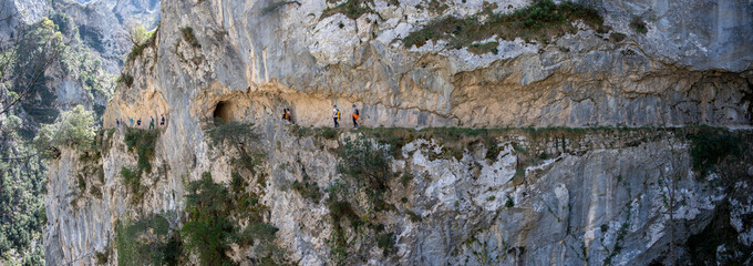 Hikers on a cliffside trail in a mountainous landscape from Ruta del Cares