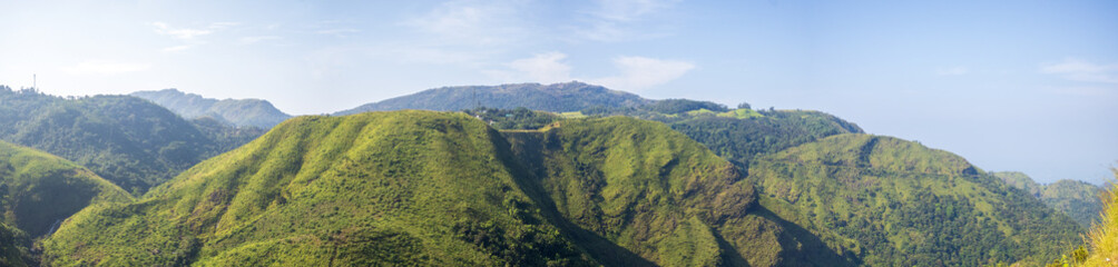 Fototapeta premium Expansive panorama of Vagamon hill station, Kerala, featuring verdant valleys and dramatic mountain ranges in daylight, perfect for beauty and adventure concepts