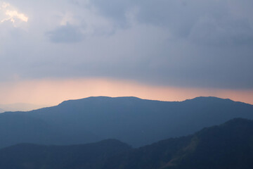 Calm Kerala mountains at sunset, blue-toned hill layers in soft light and haze, evoking peaceful wilderness and travel inspiration