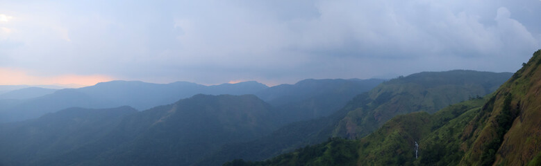 Calm Kerala mountains at sunset, blue-toned hill layers in soft light and haze, evoking peaceful wilderness and travel inspiration