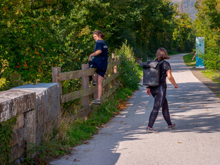 Clecy, Normandy October 4, 2025. Women walking in nature, Two women walk along a tree-lined path in Normandy, one with a backpack, the other climbing over a wooden fence