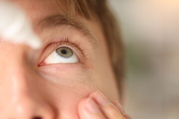 Naklejka premium Man applying eye drops on light background, closeup. Space for text