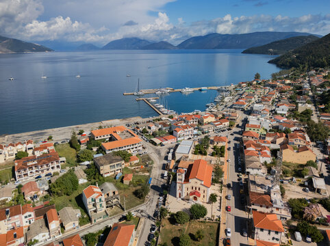 Aerial view of the terracotta rooftops of Sami cascade down to the turquoise Ionian Sea, where boats bob gently in the harbor, Sami, Cephalonia, Greece.