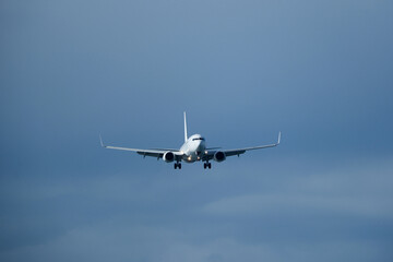 Airplane in the cloudy sky. The white plane prepares to land against a backdrop of clouds.