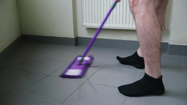 Mopping the floor. Mop washing a wooden floor in an apartment. Man clean the room