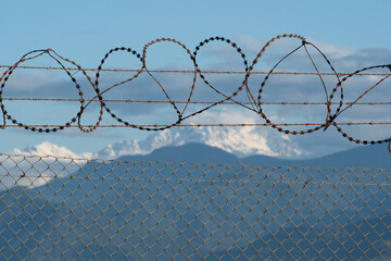 Barbed wire fence with snow capped mountains in the background. Selective focus.