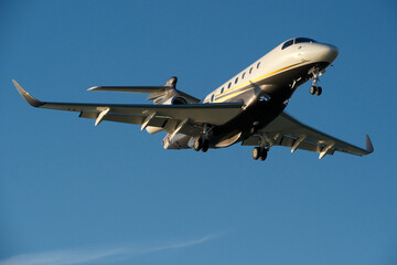 A private jet approaches the airfield against a backdrop of a partly cloudy sky. Airplane in the blue sky with white clouds.