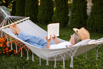 Senior woman reading book in hammock outdoors
