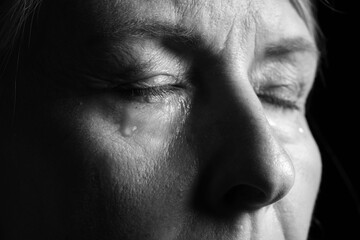 Obraz premium Senior woman crying on dark background, closeup. Black and white effect