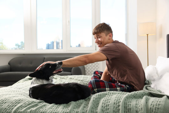 Pet friendly hotel. Man and his cute dog on bed indoors