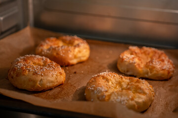Baked pastries oven, fresh golden sesame bagels baking on parchment paper, warm homemade breakfast food