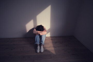 Woman sitting alone on the floor, head in her arms, depicting loneliness and depression. Mental health awareness and emotional struggle concept.