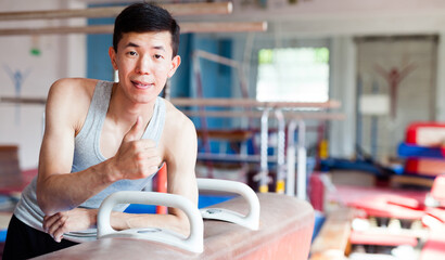 Smiling gymnast giving thumbs up after pommel horse training