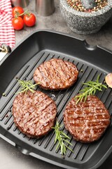 Pan with grilled patties, tomatoes and spices on grey table, closeup