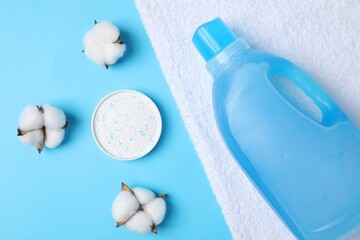 Laundry detergents, towel and cotton flowers on light blue background, flat lay