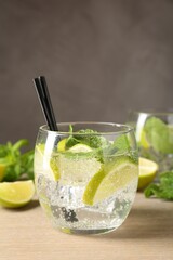 Glass of tasty cocktail with lime and mint on wooden table, closeup