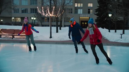 Entering from left, three friends gliding on ice under lit lampposts, woman in red jacket leading - Powered by Adobe