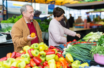  man and woman customers buying pepper in open-air market