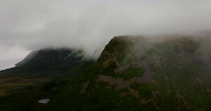Mountains shrouded in mist and fog in Vester&aring;len, arctic landscape in northern Norway. Aerial forward