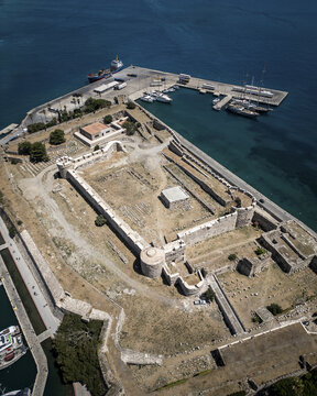 Aerial view of the Neratzia Castle's weathered stone walls meet the azure sea, where ships rest peacefully, Kos, Kos, Greece.
