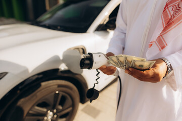 Arab man holding money and ev charger