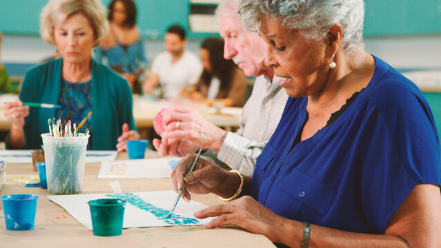 Group Of Retired Seniors Attending Art Class In Community Centre With Teacher - Powered by Adobe