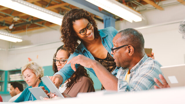 Group Of Retired Seniors Attending IT Class In Community Centre With Teacher - Powered by Adobe