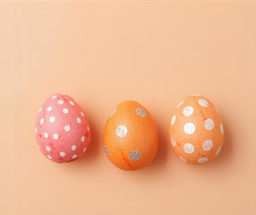 Handmade decorated pink and orange Easter eggs on peach color background