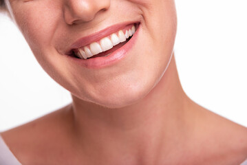 Close-up image of a smiling woman showing her white teeth and natural lips, representing happiness, confidence, and dental health.