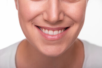 Close-up image of a smiling woman showing her white teeth and natural lips, representing happiness, confidence, and dental health.