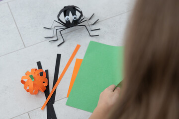 Child making a paper spider craft for Halloween at home or school. Fun DIY activity for kids, perfect for autumn classroom projects or seasonal holiday decorations.