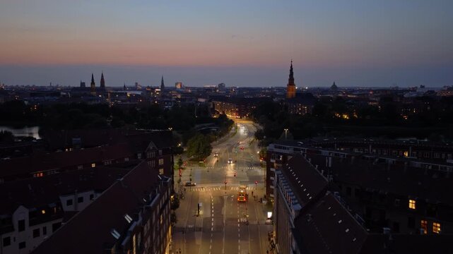 Aerial drone view of the city with car lights glowing along H.C. Andersens Boulevard and church towers in the distance in the evening in Copenhagen, Denmark