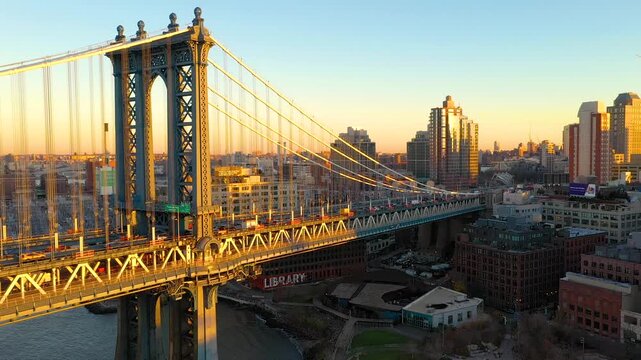 Aerial view of the Manhattan Bridge with its intricate steel structure and the city skyline bathed in the warm glow of the sunset, New York, New York, United States.