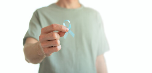 Close up of a young man holding a blue ribbon in his hand isolated over white. Symbol of prostate...