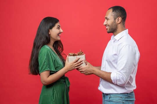 Romantic young couple standing close together woman receives surprise gift box from her boyfriend