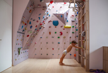  little three-year-old boy is doing warm-up exercises alone in the sports corner at home