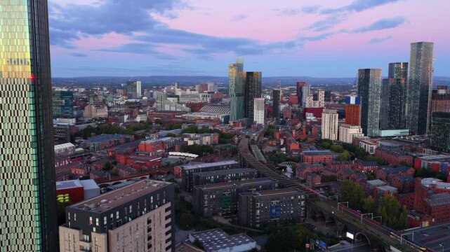 Aerial video of Manchester skyline at dusk with Trinity Islands tower, Castlefield viaduct, and Deansgate Square skyline.
