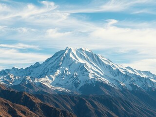 Fototapeta premium A majestic snow covered mountain peak rises powerfully against a vibrant blue sky with wispy white clouds creating an inspi view of nature's grandeur.